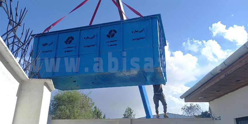 شخص بالای دیوار و استخر فایبرگلاس در حال جابجایی با جرثقیل و معلق در هوا